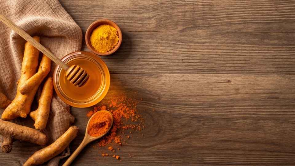 Kunyit segar dan madu asli dalam mangkuk kayu di atas meja, bahan alami untuk mengatasi khasiat kunyit dan madu bagi lambung